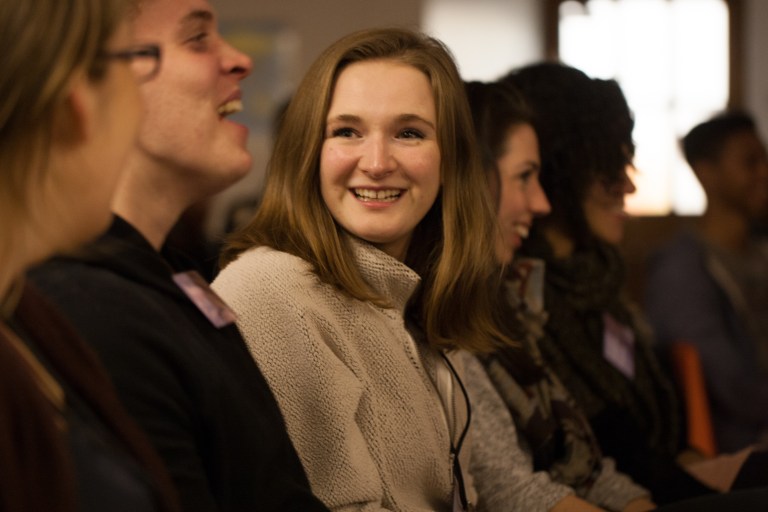 worth trusting. girl smiles in row of people.